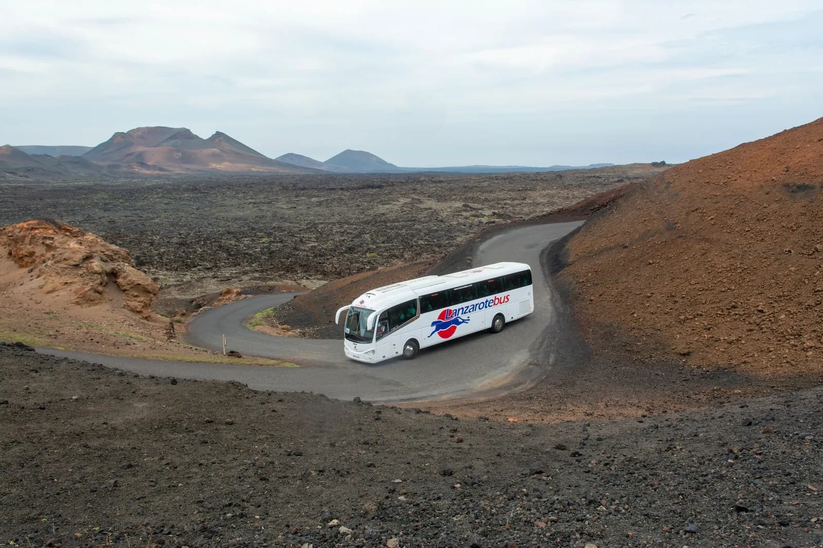 Autocar de la Ruta de los Volcanes sur la route étroite entre les coulées de lave du parc de Timanfaya