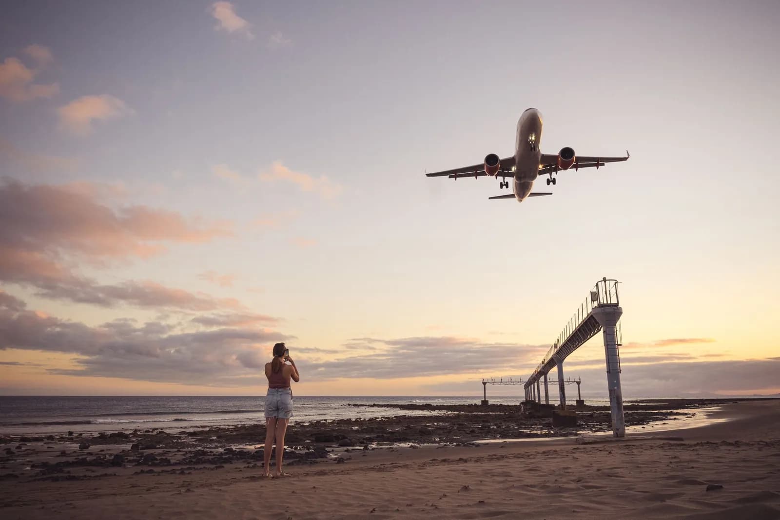 Un avion en approche finale au-dessus de la plage de Guacimeta, à Lanzarote, au coucher du soleil