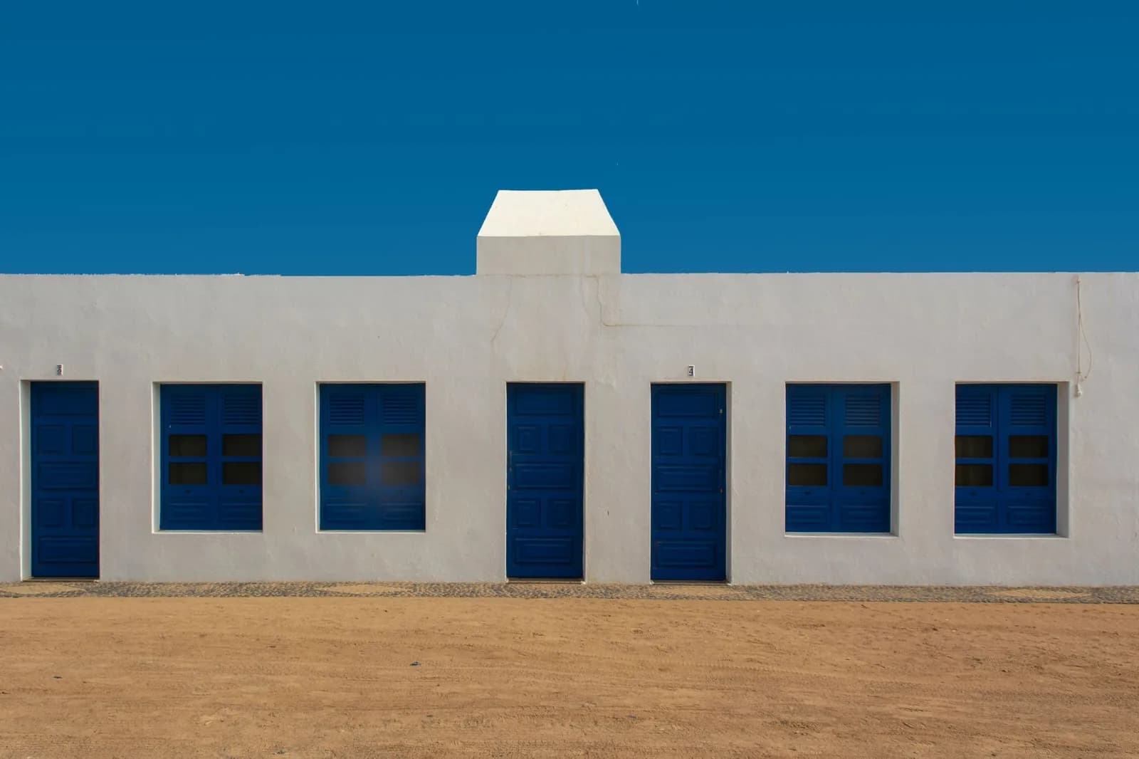 Maison blanche à portes bleues bordant une rue de sable à Caleta de Sebo, La Graciosa
