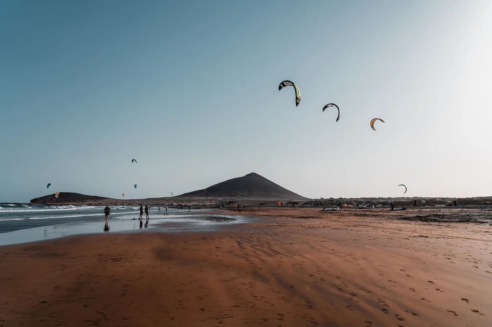 Plage d'El Médano au sud de Tenerife, avec la Montaña Roja au fond et des kitesurfeurs dans le ciel