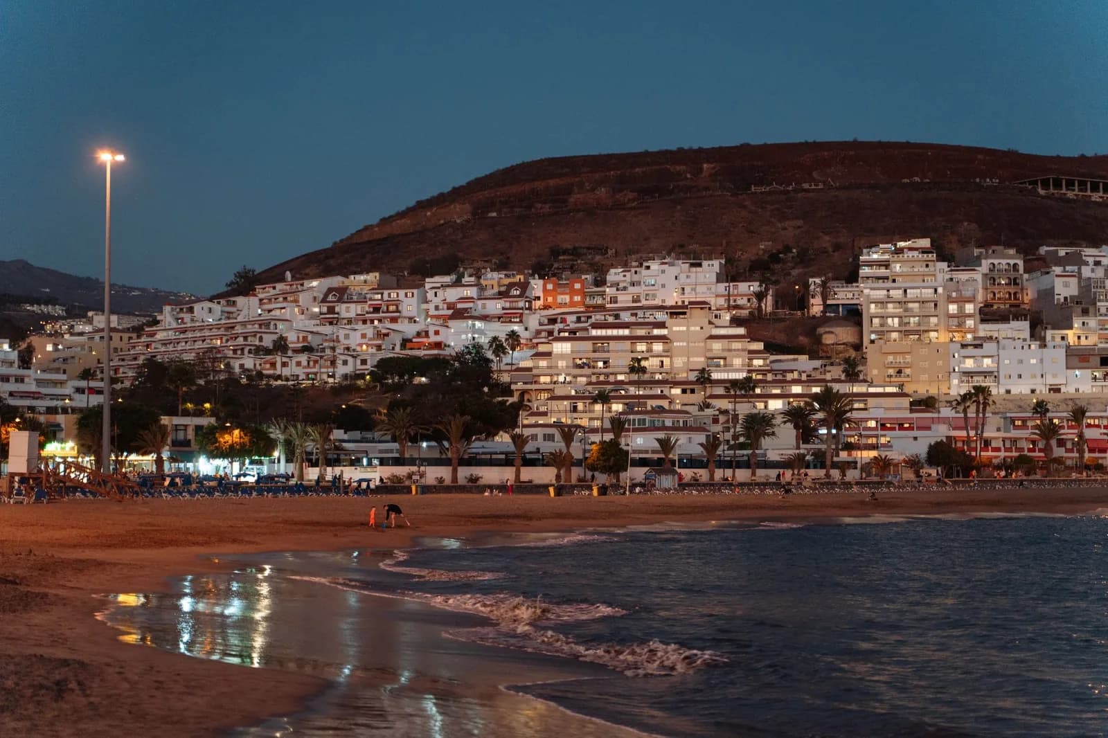 La plage de Los Cristianos à la tombée du jour, avec les immeubles de la ville sur la colline