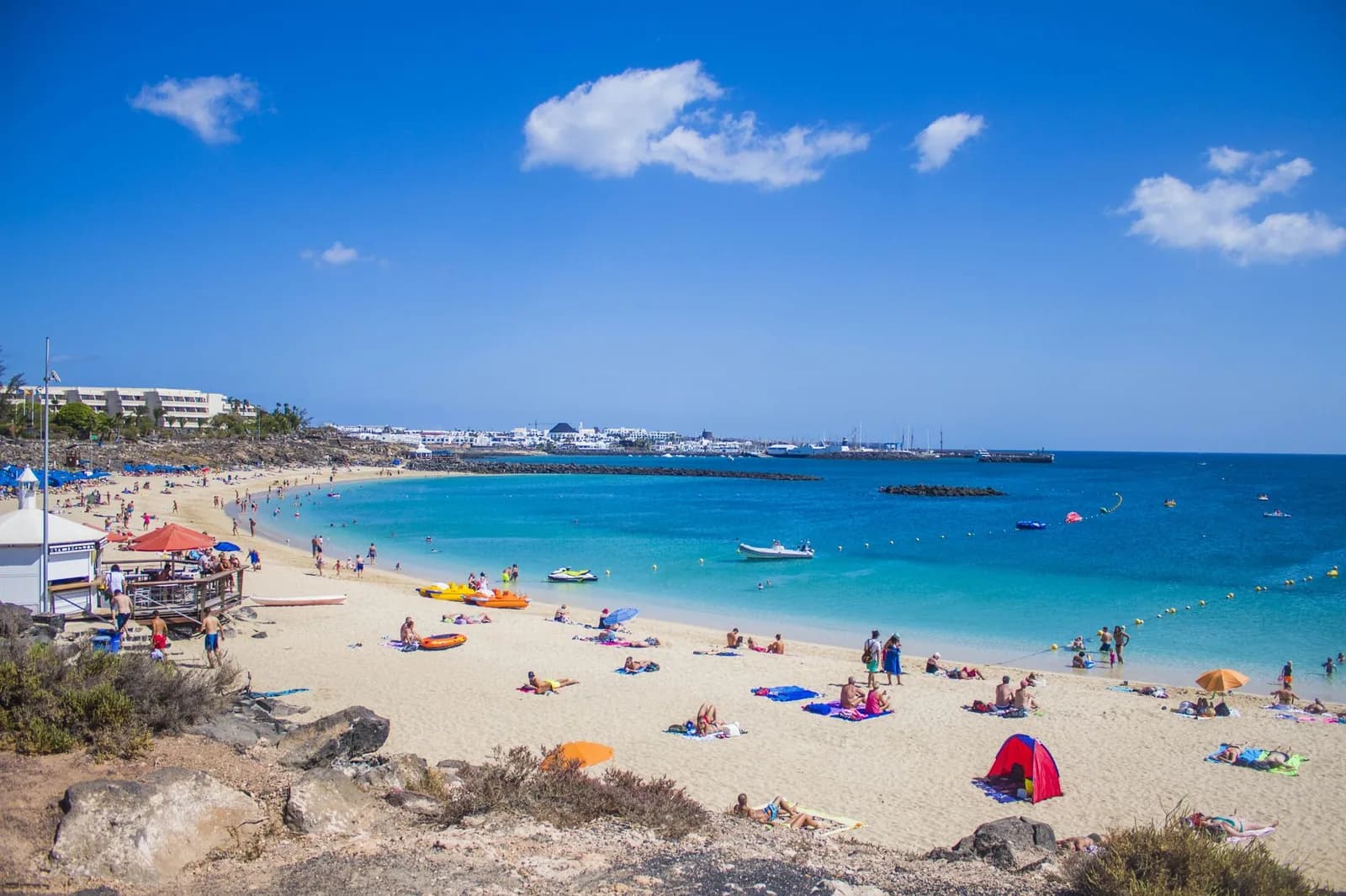 Plage Flamingo à Playa Blanca, protégée par des digues, avec des baigneurs sur une eau turquoise calme, sud de Lanzarote