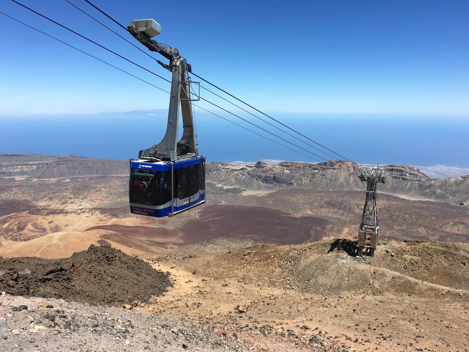 Cabine bleue du téléphérique du Teide au-dessus des coulées de lave de Las Cañadas, l'océan à l'horizon