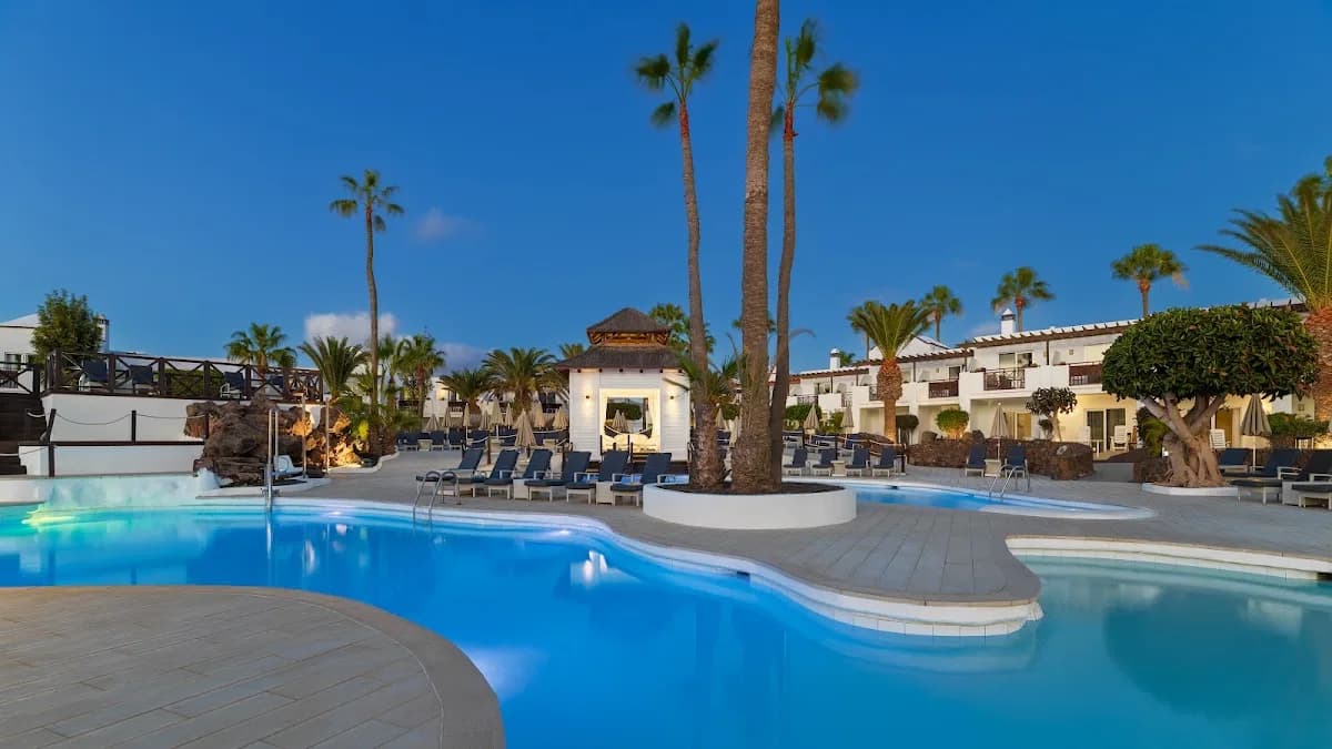Piscine et palmiers du H10 White Suites à Playa Blanca au crépuscule