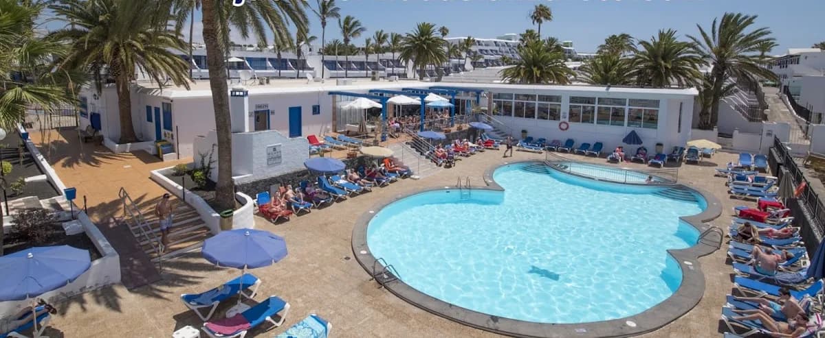 Piscine des Apartamentos Jable Bermudas à Puerto del Carmen, entourée de palmiers
