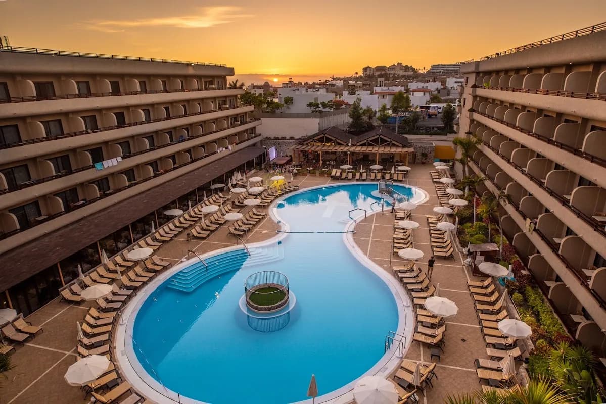 La piscine du GF Fañabé au coucher du soleil, entre les ailes de l'hôtel à Costa Adeje