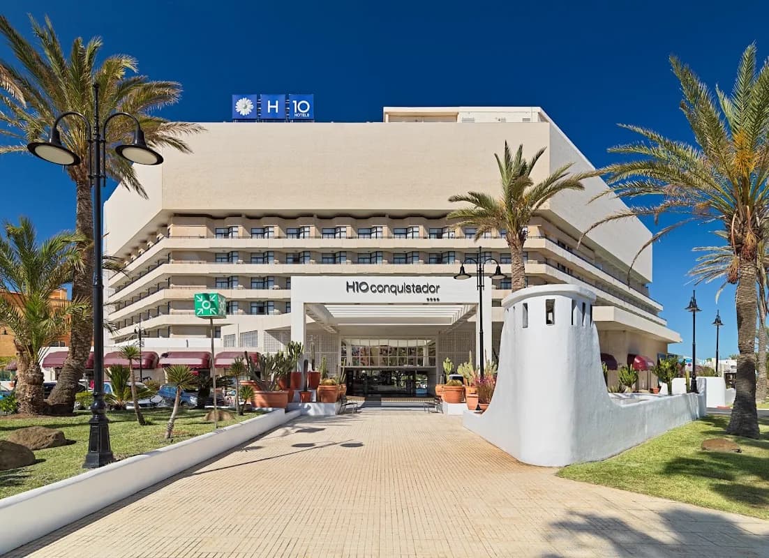La façade et l'entrée du H10 Conquistador, entre les palmiers de Playa de las Américas