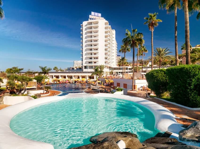Une piscine du H10 Gran Tinerfe devant la tour de l'hôtel et les palmiers