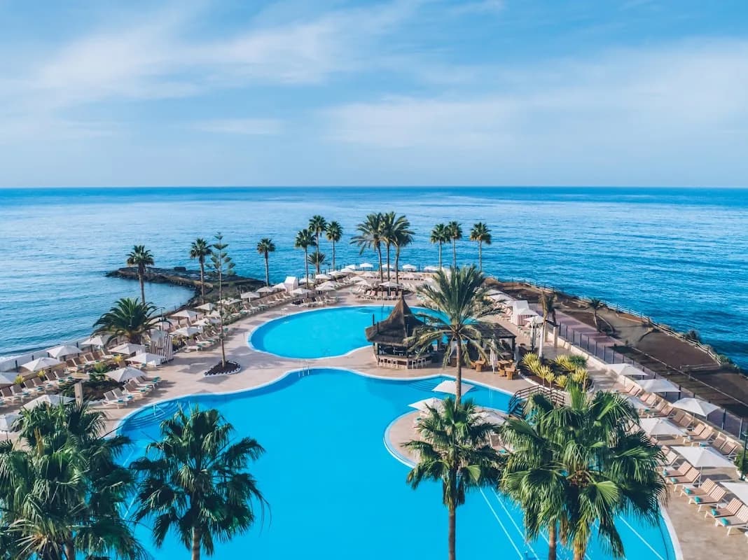 Les piscines de l'Iberostar Selection Anthelia entourées de palmiers, face à l'océan à Costa Adeje
